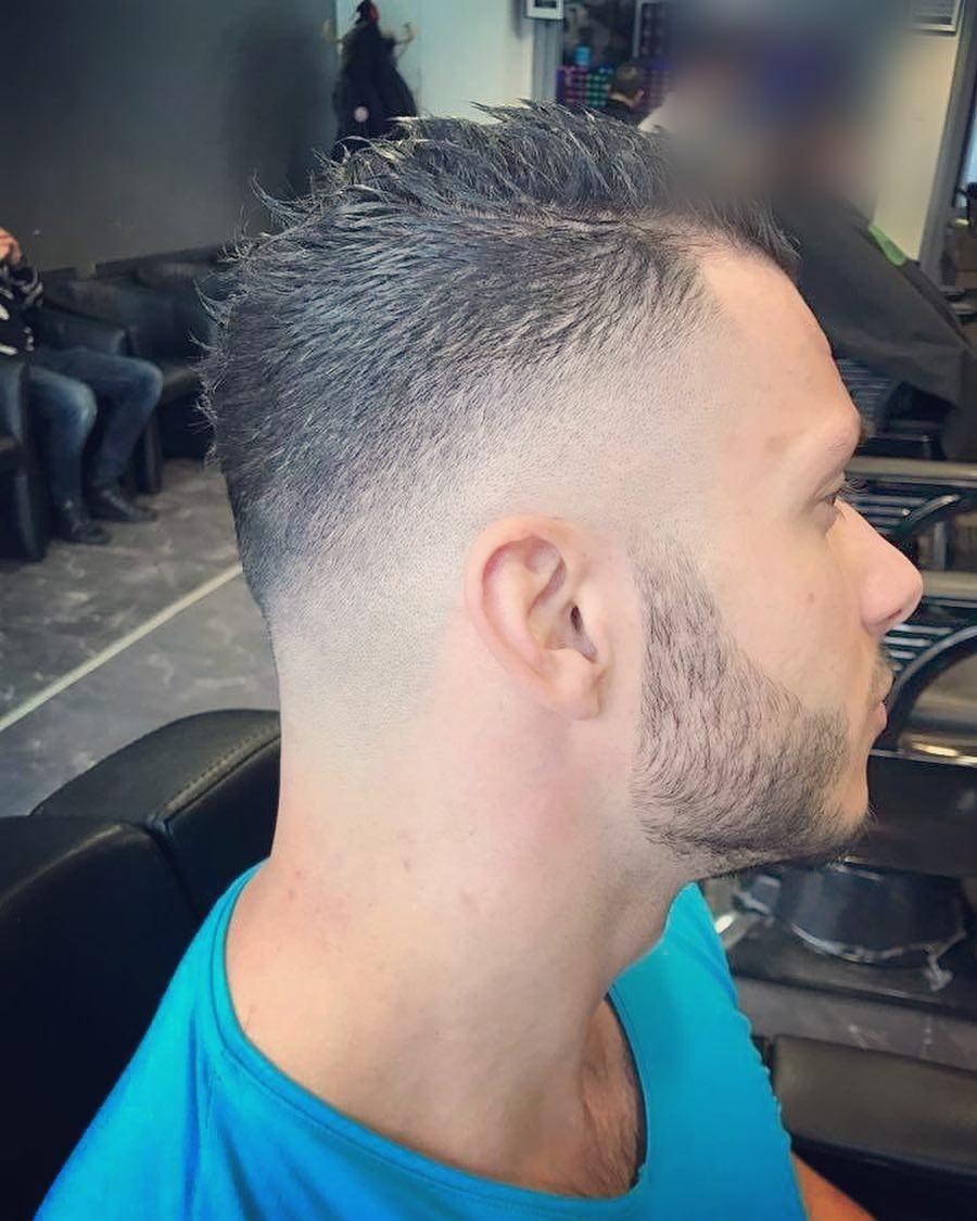 Klant in een blauw shirt met een korte fade, kort bovenop